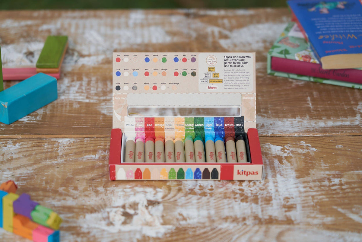 Set of colorful crayons in a box on a wooden surface