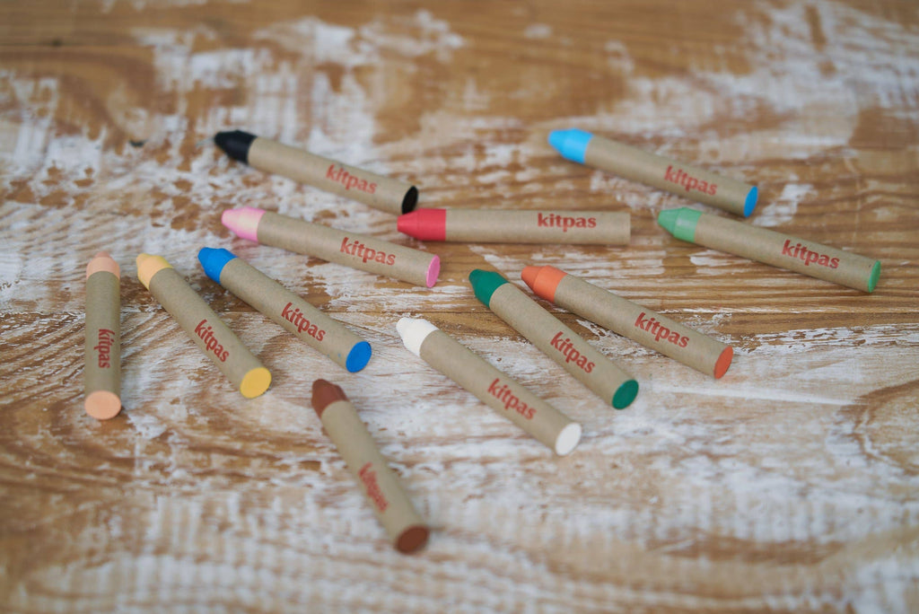 Colorful lip pencils with 'Kitpas' branding on a wooden surface