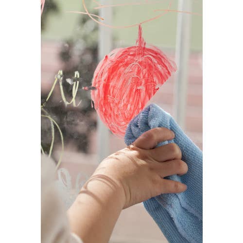 Hand holding a blue towel with a pink yarn ball hanging on a line.