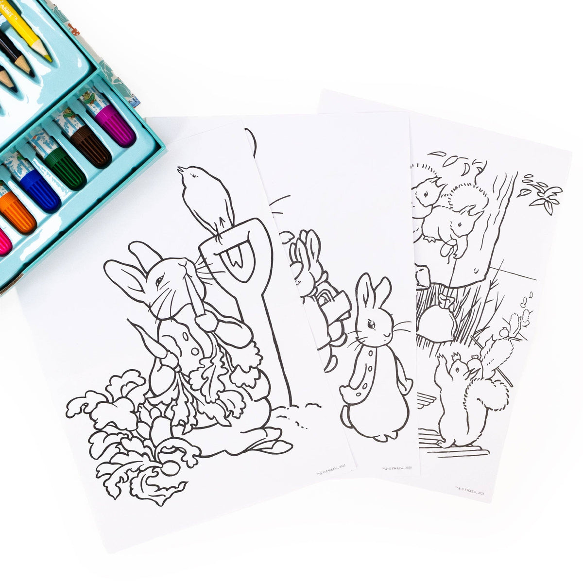 Three black-and-white illustrated colouring pages featuring rabbits and woodland animals, arranged on a white background with a teal crayon box partially visible in the top left corner.