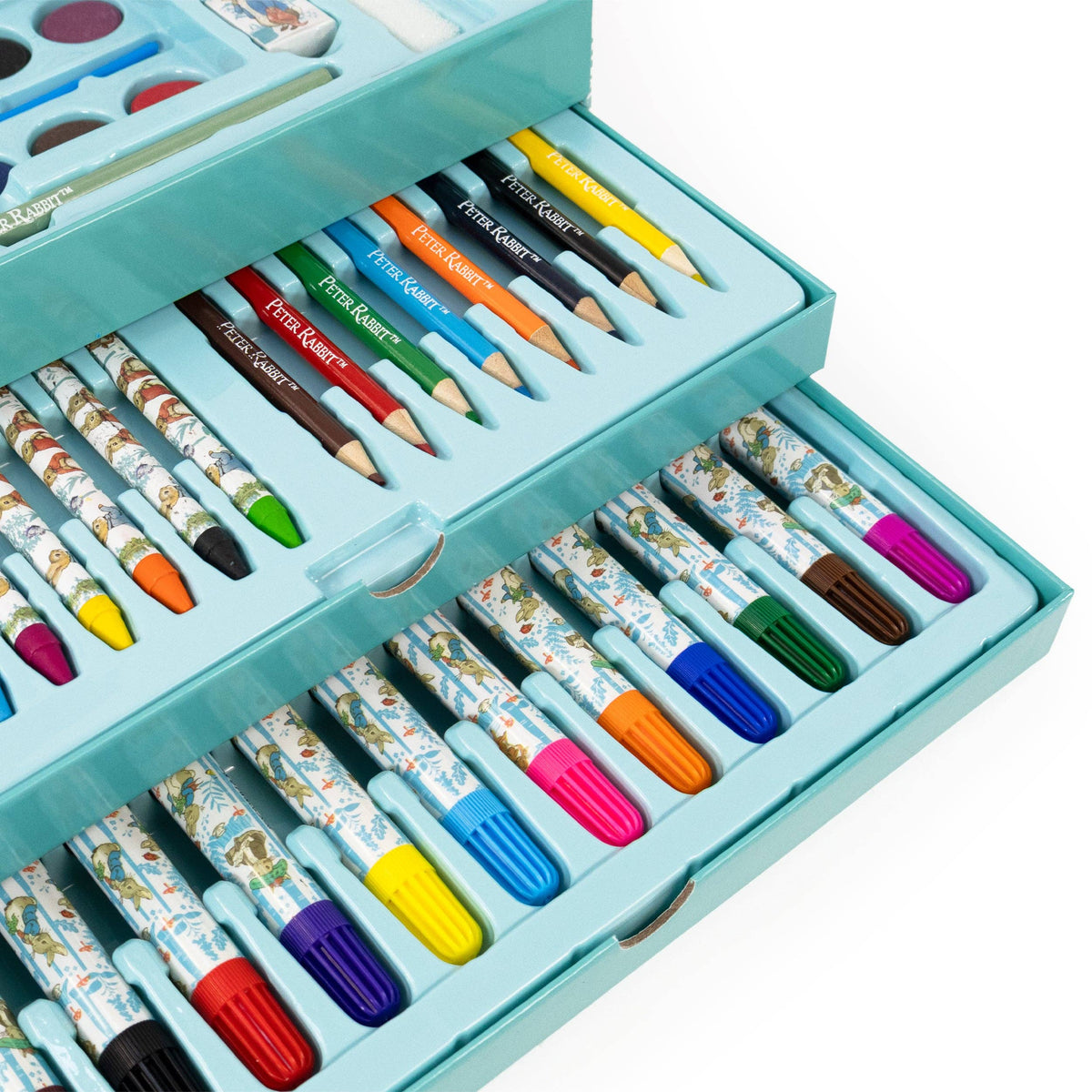 A turquoise metal art set box opened to reveal multiple compartments filled with colourful pencils, markers, and paintbrushes on a white background.