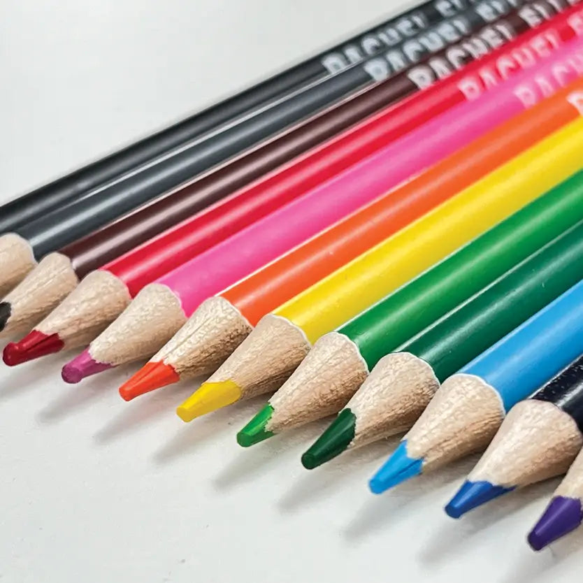 A close-up diagonal arrangement of coloured pencil tips on a white surface, showing multiple colours including black, brown, red, pink, orange, yellow, green, blue, and purple.
